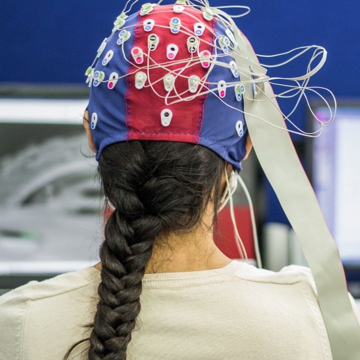 A woman with a full EEG cap on her head, undergoing a brainwave test while seated